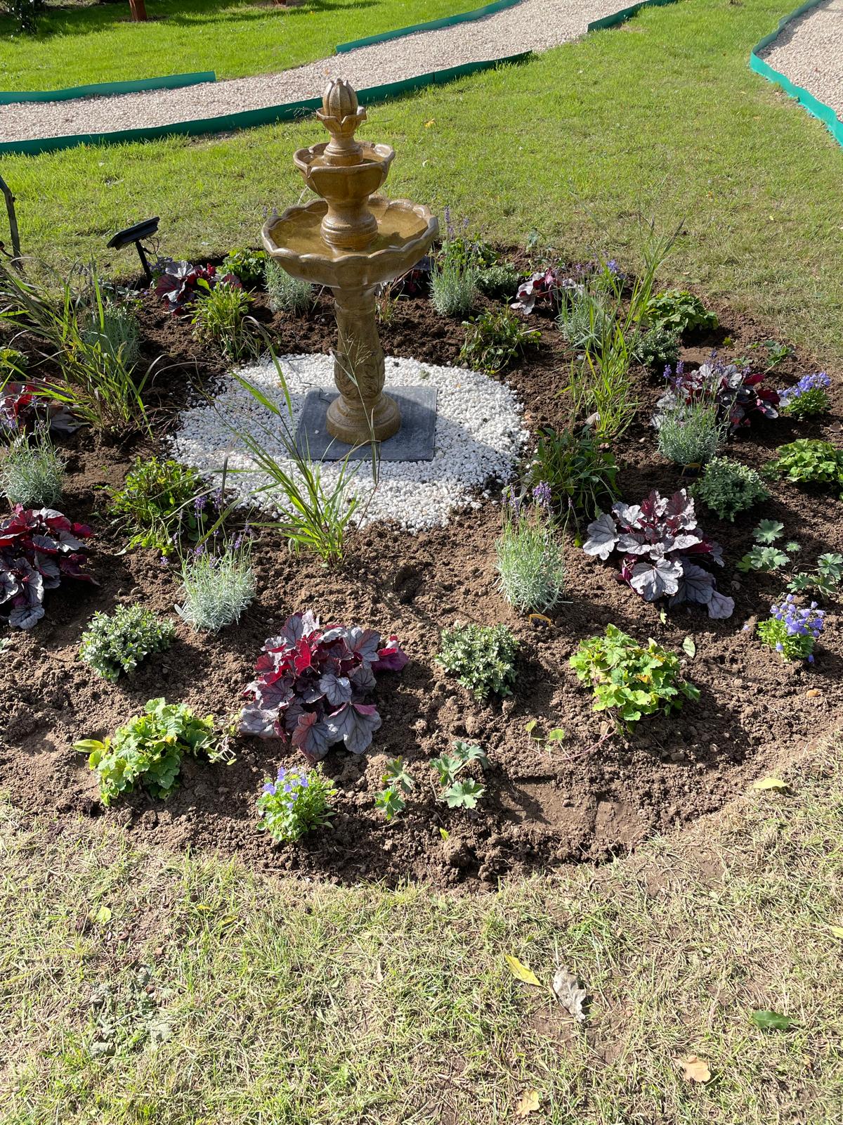 A tiered fountain surrounded by white stones and colourful planting in the Memorial Garden.