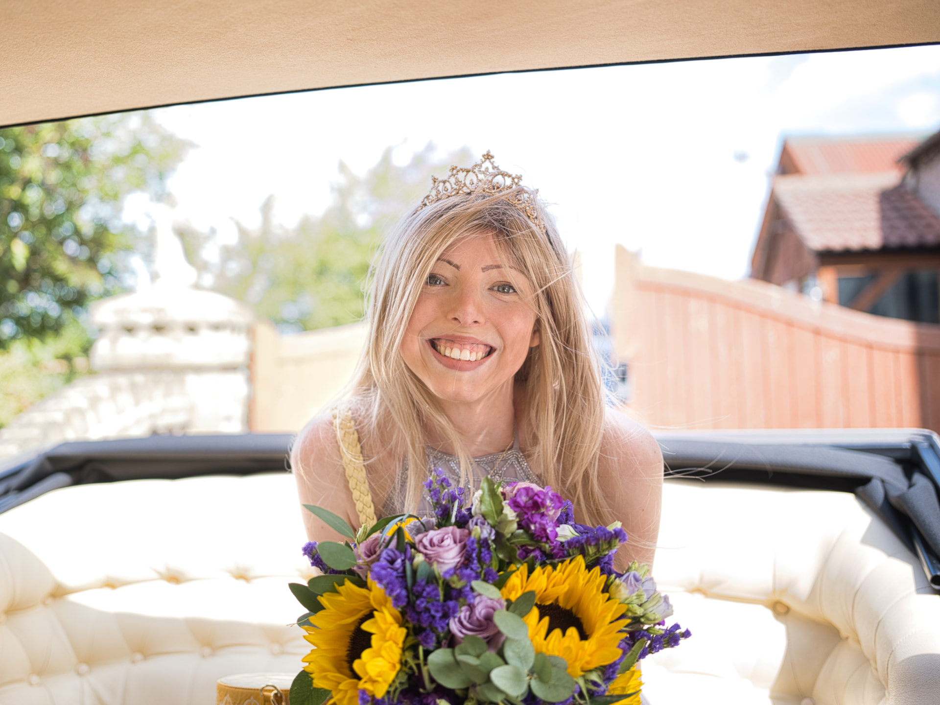 A smiling woman holding a bouquet of sunflowers, enjoying a special day made possible by a Dream